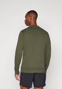 Sudadera de manga larga verde oliva con cuello redondo, tejido texturizado, puños y bajo acanalados, que presenta un pequeño detalle en la parte posterior cerca del escote.