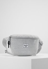 Grå tygfanny pack med strukturerad yta, dragkedjestängning, justerbar rem och en vit Herschel-logotyp på framsidan.