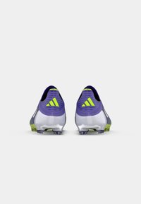 Ljubičaste i bijele nogometne kopačke s zelenim akcentima, koje imaju teksturirani gornji dio, stražnji Adidas logo i više čavlića na potplatu za prianjanje.