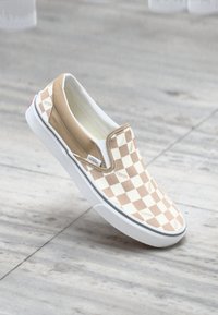 Smešne smeđe i bijele karo cipele bez kopčanja s bijelim gumenim đonom i Vans logotipom. Glatki materijal s zaobljenim vrhom i elastičnim stranama.