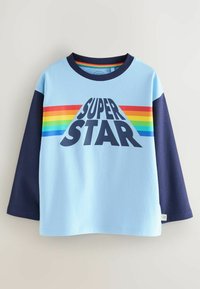 Maglietta a maniche lunghe azzurro chiaro con maniche blu navy e una grande grafica "SUPER STAR". Presenta strisce arcobaleno attraverso il petto.