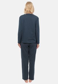 Mörkblå långärmad topp med rund hals; matchande pyjamasbyxor med prickar i mörkblått. Båda plagg är tillverkade av mjukt, luftigt material.