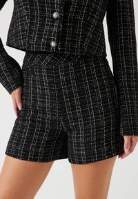 Zwart-witte geruite shorts gemaakt van gestructureerde stof, met een hoge tailleband en een taillerd snit, die schone lijnen en structuur accentueert.