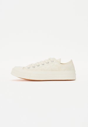 Καμβαδένια sneakers σε ανοιχτό λευκό με υφή δαντέλας, διαθέτοντας έξι θηλιές, στρογγυλή μύτη και σόλα από καουτσούκ γκωμ.
