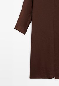 Bruine langekous met een gestructureerd oppervlak, met een rechte snit en een iets losse pasvorm. Geen zichtbare sluitingen of accenten.