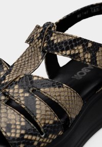 Μαύρα και καφέ σανδάλια με μοτίβο ερπετού, πολλαπλές φαρδιές λουριά και παχύ μαύρο πέλμα. Λεία υφή με ξεκάθαρες λεπτομέρειες στο μοτίβο.