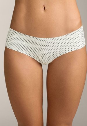 Detaljan prikaz bokova i gornjeg dijela bedara u bijelim hipster donjem rublju s crnim točkicama na jednobojnoj pozadini.