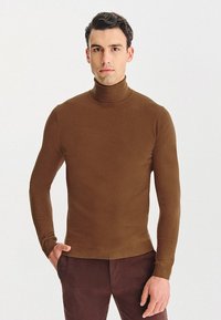 Brązowy sweter z golfem o dopasowanym fasonie, wykonany z miękkiego dzianinowego materiału. Długie rękawy i prążkowany dół. Gładka tekstura na całej powierzchni.