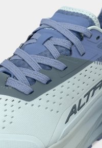 Close-up de um tênis de corrida Altra, em azul claro e cinza, com atacadores trançados e material superior perfurado e respirável.