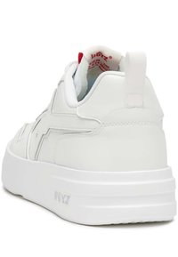 Zapatilla blanca con parte superior de cuero liso, suela blanca gruesa y un acento rojo en el interior del talón. Presenta un detalle del logo en la parte posterior.
