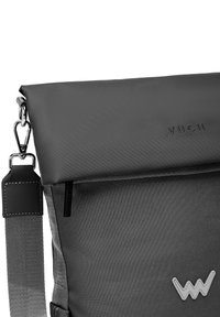 Šedá messenger taška s texturovaným povrchem, vybavená klopou na zapínání, kapsou se zipem a logem. Nastavitelný popruh s kovovými doplňky.