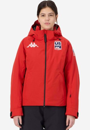 Giacca da sci rossa con cappuccio, zip nera e patch con logo. Tra le caratteristiche ci sono polsini regolabili e un esterno elegante e impermeabile.