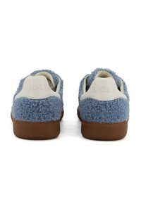 Un paio di sneakers basse con tessuto blu peloso, linguette del tallone in pelle bianca e suole in gomma marrone, viste da dietro.