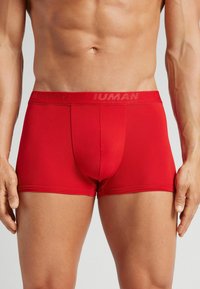Bóxers rojos para hombre hechos de una tela elástica, con una cinturilla de marca y un ajuste ceñido que se adapta al cuerpo.