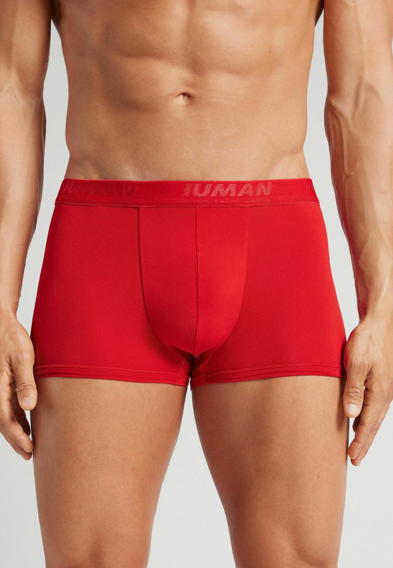 Bóxers rojos para hombre hechos de una tela elástica, con una cinturilla de marca y un ajuste ceñido que se adapta al cuerpo.