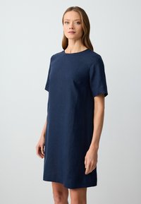 Navyblaues Leinenkleid mit kurzen Ärmeln, Rundhalsausschnitt und lockerer Passform, das eine subtile Textur und klare Linien aufweist.
