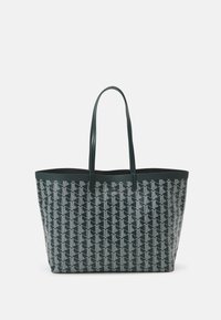 Borsa tote verde con un motivo geometrico bianco, realizzata in materiale resistente. Presenta due manici lunghi e un design a apertura superiore.
