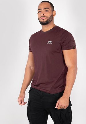 Burgundy t-shirt with short sleeves, round neckline, and a small white logo on the chest, paired with black cargo pants.