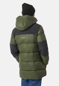 Olive green puffer jacket with a black grid pattern on shoulders and sleeves. Features a hood and stitched sections for insulation.