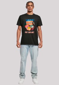 Black cotton T-shirt featuring a graphic design with colorful illustrations and text, paired with light blue denim jeans and white sneakers.