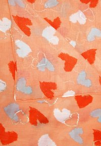 Oranje sjaal met een textuur van hartpatronen in rood, wit en lichtblauw. Lichtgewicht stof met een iets doorzichtige kwaliteit.