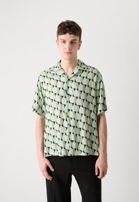Rövid ujjú gombos ing menta zöld színben, sötétzöld geometriai mintával, laza fazonnal és kivágott gallérral.