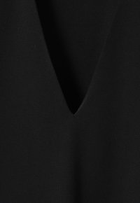 Black V-neck garment made of smooth, stretchy fabric; features a deep V shape and a solid color with no patterns or visible hardware.