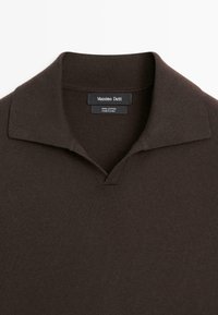 Dark brown cotton polo shirt collar with Massimo Dutti label and "100% cotton made in China" tag visible.