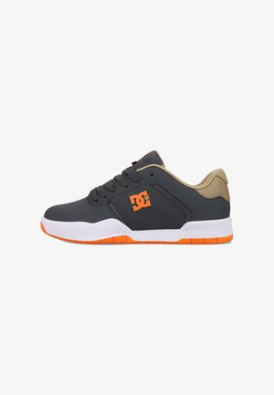 Zapatillas bajas en gris oscuro con detalles en beige, suela naranja y detalle del logo. Cuentan con un diseño de cordones y un cuello acolchado para mayor soporte.