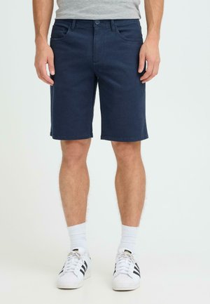 Marineblå bomuldsshorts med en lige ben-design, bæltestropper og subtile syningsdetaljer, kombineret med hvide sokker og sneakers med sorte striber.