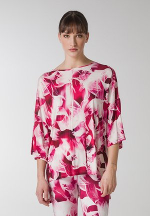 Top lejer, dintr-un material ușor, cu un model floral în nuanțe de roz și alb. Dispune de mâneci largi și de un decolteu în formă de barcă. Este asortat cu pantaloni potriviți.