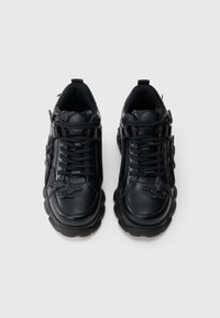 Baskets en cuir noir avec détails texturés, semelles arrondies et lacets noirs. Présentent un détail décoratif en forme de papillon sur les côtés.