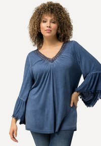 Top in denim blu con scollo a V e raffinato bordo in pizzo, maniche a campana e vestibilità comoda. Tessuto morbido e design leggero.