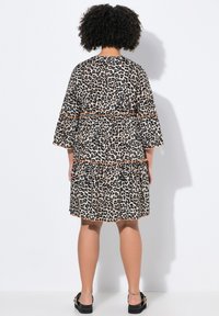 Vestido con estampado de leopardo, mangas campana cortas, diseño con volantes, detalles naranjas y corte holgado. Confeccionado con tela ligera.