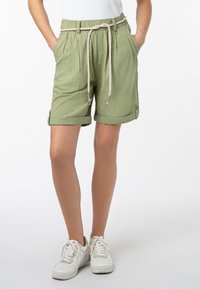 Green linen shorts with a drawstring waist, rolled-up cuffs, and side pockets. Worn with white sneakers.