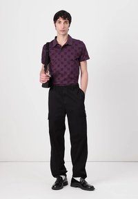 Polo majica s kratkimi rokavi v temno vijolični barvi s patterned oblikovanjem, v kombinaciji s črnimi cargo hlačami in črnimi poslovnimi čevlji.