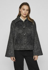 Pelēka teksturēta vilnas samaisa jaka ar apkakli, pogu aizdari un divām priekšējām kabatām. Iezīmē plašas piedurknes un īsāku dizainu.