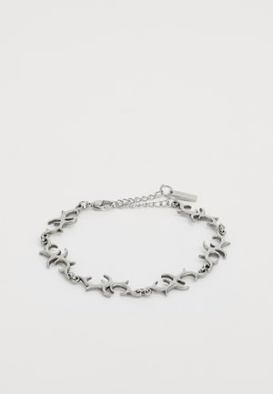 Silver metal bracelet with connected abstract tribal-style links and a small rectangular tag near the clasp on a white background.