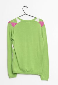 Grön tröja med långa ärmar, med rosa och vita geometriska mönster på axlarna. Mjuk stickad material, rund halsringning och ribbade manschetter.