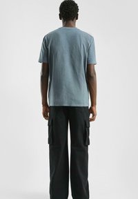 Blauwe katoenen T-shirt met korte mouwen, ronde hals en een vervaagde afwerking, gecombineerd met zwarte cargo pants met zijzakken.