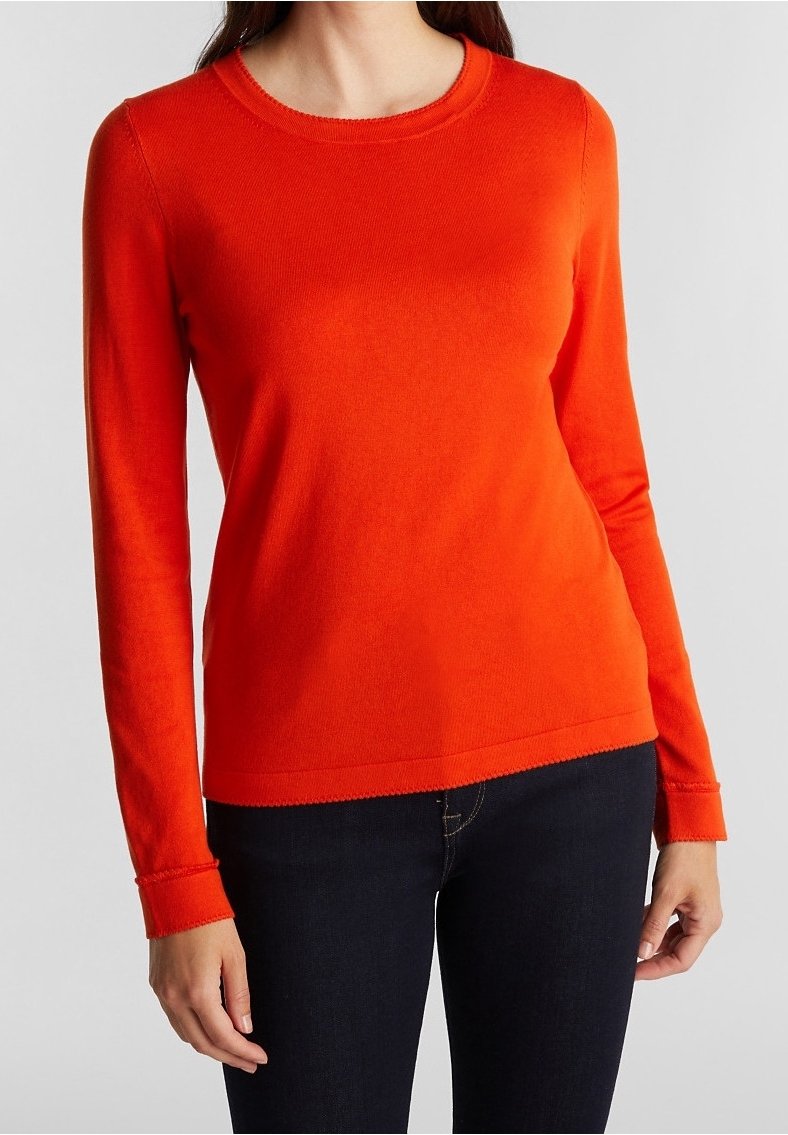 Red long-sleeve sweater made of soft knit fabric, featuring a round neckline and ribbed cuffs, paired with dark jeans.