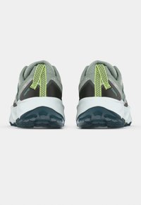 Chaussures de sport grises et noires avec une tige texturée, dotées d'une languette de tirage au talon vert vif et d'une semelle en caoutchouc à motifs.