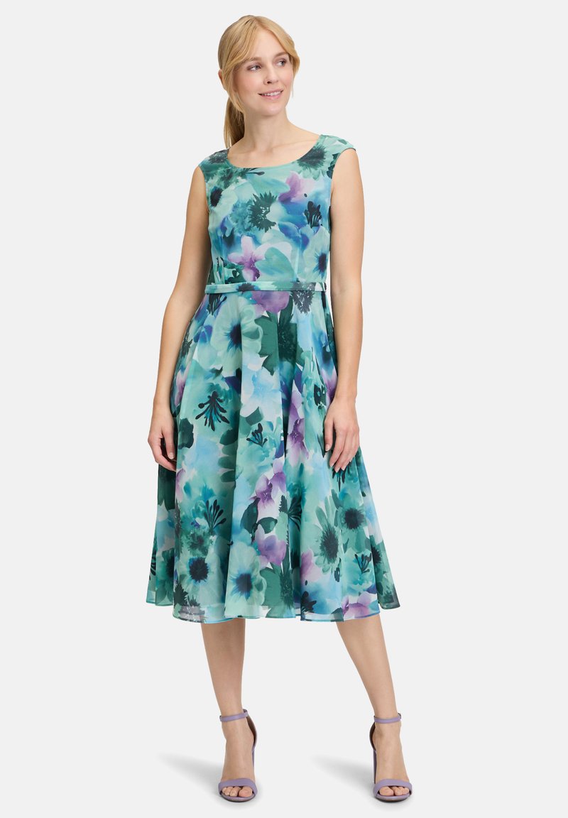 Blumenkleid mit einem Design in Teal, Grün und Lila, das einen taillierten Oberteil und einen ausgestellten Rock hat, aus leichtem Stoff gefertigt.