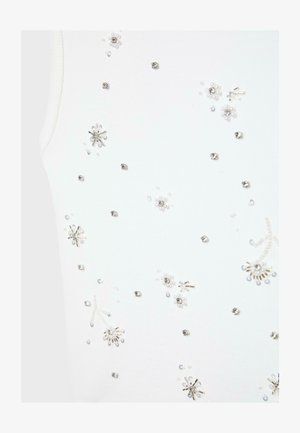 Tessuto bianco con piccoli ornamenti floreali di perline argento e perla disposti a uno schema delicato.