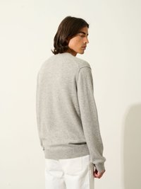 Ljusgrå tröja gjord av mjukt tyg, med rundad halsringning och ribbad fåll. Baksidan visar långa ärmar och en enkel design.