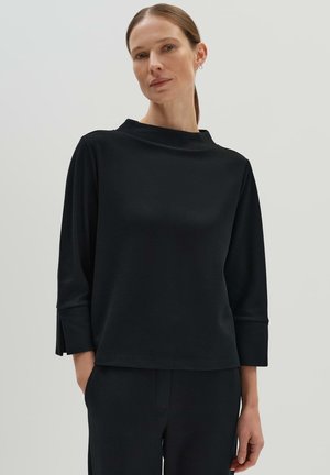 Zwarte lange mouw top met een hoge halslijn en zijopeningen. Gemaakt van textuurstof, met een ontspannen pasvorm en minimalistisch ontwerp.