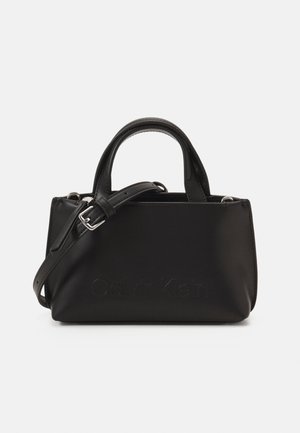 Sac à main rectangulaire noir avec poignées supérieures, bandoulière réglable et nom de marque subtilement embossé à l'avant.