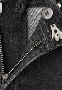 Čierna džínsová bunda z blízka so strieborným zipsom, čiernym gombíkom a textúrovanou tkaninou. Viditeľné prešitie a detail vnútornej podšívky.