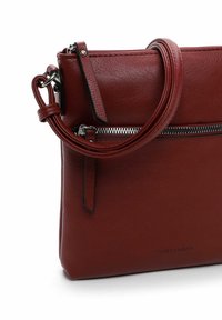 Rote Ledertasche mit einem Reißverschlussfach, glatter Textur, rechteckiger Form, rundem Griff und subtilen Logodetails auf der Vorderseite.