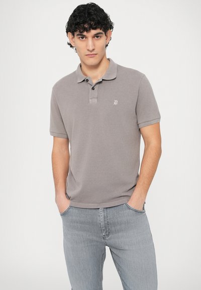 Γκρι πόλο πουκάμισο με γιακά, διαθέτει τρία κουμπιά στο μπούστο και ένα μικρό λογότυπο στο στήθος, συνδυασμένο με ανοιχτό γκρι τζιν παντελόνι.